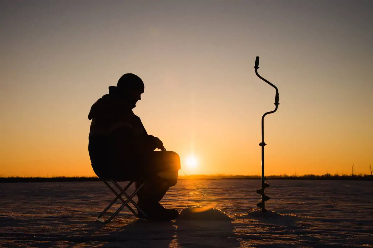 Photo of a Silhouette Man Ice Fishing on a Bucket